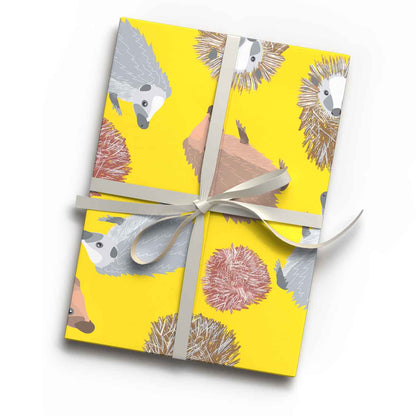 Bright yellow hedgehog animal print luxury gift wrap sheet shown wrapping a gift